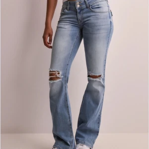 Ljusblå lågmidjade jeans med slitningar - Säljer ett par ljusblå bootcut jeans med slitna detaljer vid knäna. Perfekta för en avslappnad och trendig look. Knappt använda då det var fel storlek. Bara att skriva för fler bilder💞