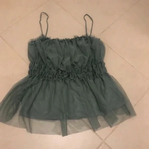 Grön topp med tunna axelband - Säljer en ljusgrön, volangig linnetopp med tunna axelband och rynkade detaljer i midjan. Perfekt nu till sommaren💗