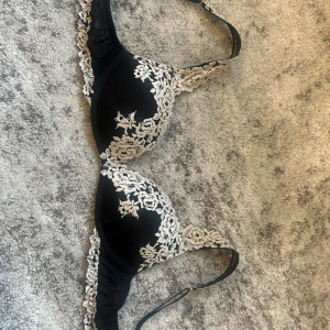 intimissimi - Säljer en svart bh från Intimissimi med vacker vit spetsbrodyr. Bh:n har tunna axelband och fina spetsdetaljer längs kanterna. Perfekt för dig som gillar en elegant och feminin stil.