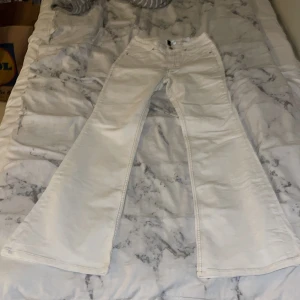 Vita bootcut jeans från H&M - Snygga vita bootcut jeans från H&M med klassisk femficksdesign och knappgylf. Perfekta för en stilren look med en touch av retro. Passar bra till både sneakers och klackar.Är midwaist typ..Obs!!Fast pris 150kr!!!