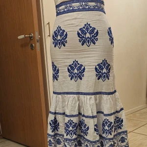 Zara kjol  - Charmig vit kjol med blått mönster. Kjolen har en volangdetalj och når till knäna. Perfekt för en somrig look med sina vackra blåa mönster som ger en fräsch känsla. Kjolen är endast testad men tyvärr pris etiketten är borta.                             Pris: 450    