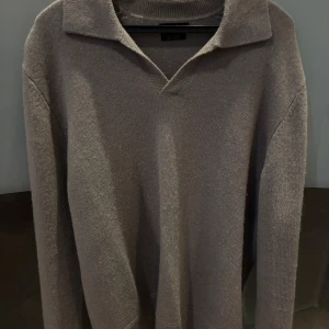 Grå stickad tröja från Massimo Dutti - Säljer en stilren grå stickad tröja från Massimo Dutti i mjuk kashmirblandning. Tröjan har lång ärm, krage och v-ringad halsringning för en klassisk look. Perfekt för lager-på-lager och passar till många outfits.