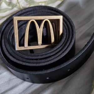 Svart mcdonalds bälte  - Svart mcdonalds bälte, andvänt några gånger. Justerbar. Bältet är 120 cm långt.