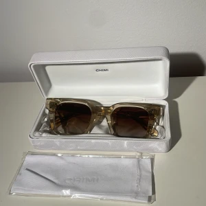 Chimi 04 ecru  - Snygga transparenta solglasögon från Chimi med fyrkantig form och mörka linser. Perfekta för en stilren look. Kommer med ett vitt fodral och putsduk. Vid frågor är det bara att komma privat och pris kan diskuteras vid snabb affär.