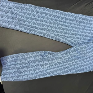 Mönstrade byxor från Lacoste - Snygga blå byxor från Lacoste med ett unikt geometriskt mönster. Byxorna har en elastisk midja och en liten broderad logotyp. Perfekta för en avslappnad stil.