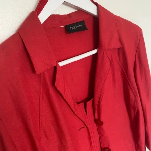 Röd klänning med kavaj från Gianini - Röd klänning med matchande kavaj från Gianini. Jag köpte detta set på second hand för 150kr till temafest. Skavanker finns. Storlek bortklippt men skulle gissa M
