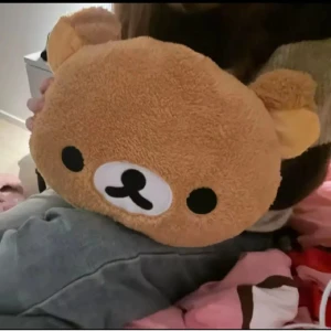 Brun Rilakkuma nalleformad kudde habdvärmare  - Söt och mjuk kudde / handvärmare i form av en brun Rilakkuma nalle. Perfekt för att bära med sig småsaker på ett gulligt sätt. Väskan har ett ansikte med svarta och vita detaljer.