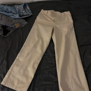 Sweet sktbs- Beige chinos med raka ben  - Snygga beige chinos med raka, lite vidare ben och klassisk passform. Byxorna har hällor för bälte och stängs med dragkedja och knapp. Perfekta för en clean och stilren look.