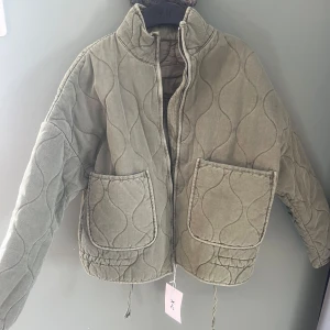 Olivgrön quiltad jacka från X.C - Säljer denna olivgrön quiltad jacka från X.C, eftersom den var för liten för mig. Den har två stora framfickor och dragkedja. Jackan har hög krage men vågiga mönster. Aldirg använd och prislappen finns kvar. Nyligen köpt också! 