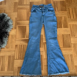 Blå bootcut jeans från SHEIN M - Snygga blå bootcut jeans från SHEIN i storlek M. Hög midja och utsvängda ben med råa, fransiga benslut för en trendig look. Klassisk femficksmodell och tillverkade i bomullsmix. Perfekta för dig som gillar retrovibbar och statement-jeans.