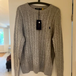 Stickad Ralph Lauren tröja - Tja, säljer min Polo Ralph Lauren kabelstickade tröja. Den är i nyskick med lappar på, inprincip oanvänd. Är 186cm lång och väger 70kg.  Pris kan diskuteras vid snabb affär. Om ni är intresserade är de bara att höra av sig, Loke