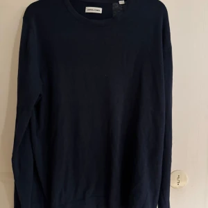 Mörkblå tröja från Jack & Jones - En stilren mörkblå tröja från Jack & Jones med rund halsringning och långa ärmar. Tröjan är tillverkad i mjuk bomull och har en klassisk passform som funkar till många olika outfits.