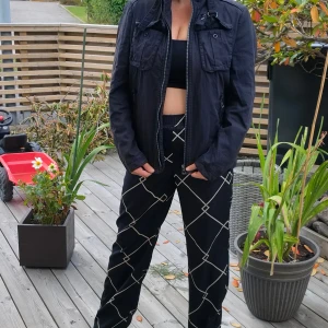 Boss Svart vindjacka med dragkedja stl M - Svart vindjacka med hög krage, dragkedja framtill och flera fickor med lock och dragkedja. Jackan har en clean och stilren look, perfekt till streetwear. Långärmad och i ett lätt material som passar bra till vår och höst.