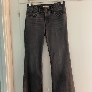 Levi's Superlow Flare svart/grå jeans - Snygga svart/grå Levi's Flare jeans. Jeansen har låg midja och utsvängda ben. Midja 27, längd 34. Jag är 167 cm dom åker i golvet. Vet ej fraktkostnaden.