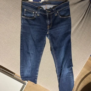 Mörkblå Nudie Jeans - Snygga mörkblå jeans från Nudie Jeans med klassisk femficksdesign och kontrastsömmar. Jeansen har raka ben och normal passform, tillverkade i slitstarkt bomullstyg. Bakfickan har Nudie Jeans ikoniska broderi i gult. Schyssta Jeans pris 450kr 8/10 skick. sSkjälvklart äkta. Har du några frågor är det bara att skriva nedan. Skickas inom 48 timmar🤩🤩