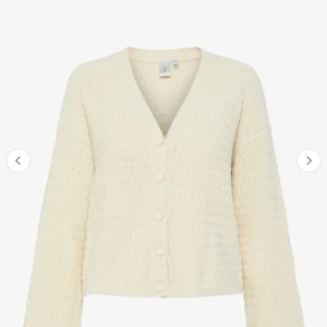 Beige stickad kofta från boozt - Säljer en beige stickad kofta från boozt, märket är Was,  med v-ringning och knappar framtill. Koftan har ett snyggt hålmönster, långa ärmar och croppad passform som ger en chill vibe. Perfekt att slänga över en t-shirt för en enkel och fräsch look. Använd en gång!