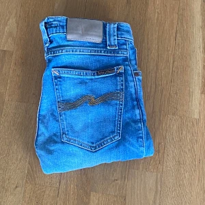  jeans från Nudie Jeans - Snygga Nudie Jeans – Bra skick! Klassiska blå jeans från Nudie Jeans Co med ikonisk bakficka. Sitter grymt bra och passar till allt! Sparsamt använda – inga fläckar eller hål.  📏 W26 L32 🎁 Snabb leverans! 