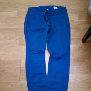 Blå byxor från Amisu, storlek 40 - Snygga blå byxor från Amisu i storlek 40. De har en klassisk femficksmodell och är tillverkade i ett mjukt bomullsmaterial med lite stretch. Passformen är rak och de har normal midja. Perfekta för en chill och stilren look.
