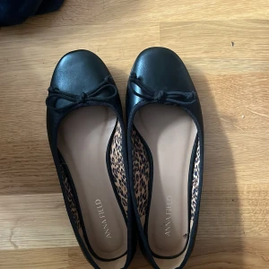 Svarta ballerinaskor från Anna Field - Snygga svarta ballerinaskor från Anna Field med rund tå och dekorativ rosett framtill. Insidan har ett coolt leopardmönster som ger extra edge. Skorna är i syntetmaterial och har platt sula, perfekta för en stilren look. Säljer då de är förstora för mig, jag har i vanliga fall 37 men på Anna field har jag 35💓