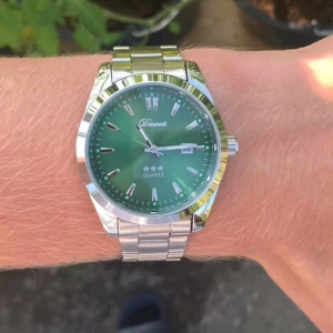 Grön klocka från Doventi med stållänk - Snygg klocka från Doventi med grön urtavla och datumvisning. Klockan har en klassisk rund form och en länk i blankt silverfärgat stål. Quartz-urverk och stilrena indexmarkeringar gör den både modern och tidlös. Perfekt accessoar för dig som vill sticka ut lite extra.