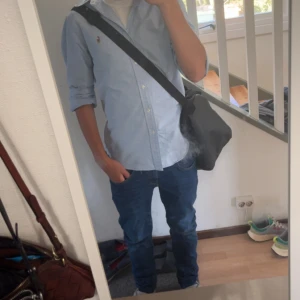 Ljusblå skjorta från Ralph Lauren - Klassisk ljusblå skjorta från Ralph Lauren med button-down krage och broderad logga på bröstet. Skjortan har långa ärmar och knäppning framtill. Perfekt för en clean och stilren look.