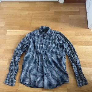 Grårutig skjorta från Dressmann M - Blårutig skjorta från Dressmann Premium Collection i storlek M, 39/40 krage. Tillverkad i 100% bomull.