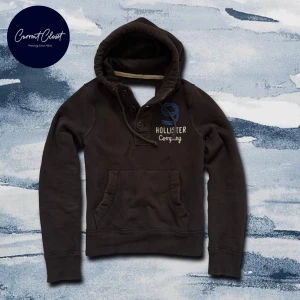 Brun hoodie från Hollister med brodyr - Mörkbrun hoodie från Hollister med broderad blå siffra och text på bröstet | Size S | Har nästan inga defekter trots vintage!