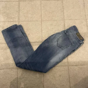 Blå Replay jeans med raka ben - Snygga blå jeans från Replay med klassisk femficksdesign och raka ben. Jeansen har en lätt tvättad look med subtila slitningar och normal passform. Perfekta till vardags och funkar till det mesta. Materialet är mjukt och skönt jeans-tyg.små i storlekarna
