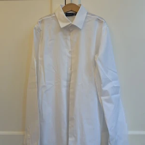 Vit skjorta från Dal Lago i bomull - Klassisk vit skjorta från Dal Lago, tillverkad i Italien av 100% bomull. Skjortan har lång ärm, knappar framtill och en stilren krage. Perfekt för dig som gillar en clean och tidlös look.