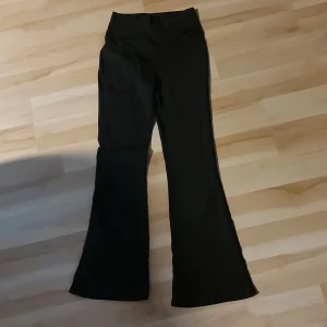 Svarta bootcut byxor med hög midja - Snygga svarta träningsbyxor med bootcut och hög midja. De har en klassisk siluett med utsvängda ben och är tillverkade i ett stretchigt material som sitter bekvämt. 