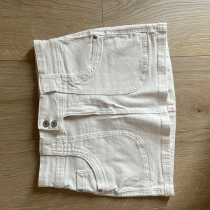 Vit jeanskjol från Bershka strl 36 - Snygg vit jeanskjol från Bershka med snygga,klassiska fickor. Shortsen har silverfärgade knappar framtill och är gjorda i ett mjukt bomullsmaterial. Perfekt basic kjol som passar till mycket. Super fin! Strl 36 men skulle säga att den är liten i storleken så passar även 34 💗
