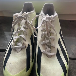 Adidas vita fotbollsskor strl 42 1/2 - Snygga vita fotbollsskor från Adidas med svarta ränder och limegula detaljer. Skorna har klassisk snörning och är tillverkade i syntetmaterial med meshfoder för extra komfort. Perfekta för dig som vill sticka ut på planen. Pris går att diskutera!