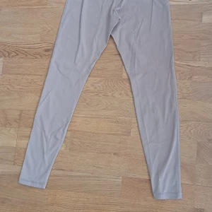 Beige leggings från ICANIWILL, S - Snygga beige leggings från ICANIWILL med hög midja och vita detaljer längs sidorna. Tillverkade i ett stretchigt material av 75% nylon och 25% spandex som sitter tight och bekvämt. Perfekta för träning eller chill dagar.