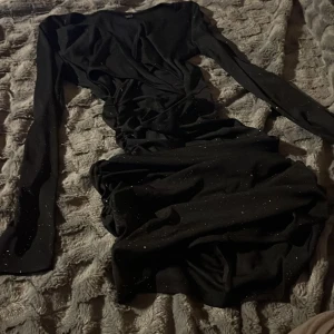 Svart glittrig kortklänning från SHEIN - Säljer en svart kortklänning från SHEIN i storlek S. Klänningen har långa ärmar, glittriga detaljer och är figurnära med rynkade partier. Materialet är ribbat och stretchigt. Scrusch i rumpan. Endast använd 1 gång 