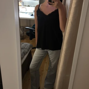 Svart linnetopp med spets - Svart linnetopp från Amisu med tunna axelband och v-ringning med spets. Toppen har en lös passform och är perfekt för en stilren. Den är lite nopprig men inget som syns super mycket. Skriv privat för mer bilder💋