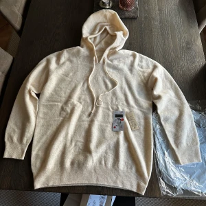 Kashmir hoodie i ljusbeige - Supermjuk beige hoodie i lyxig kashmir med huva och snörning. Tröjan har ribbade muddar och en clean, minimalistisk look! Jag köpte tröjan men modellen var mindre irl, så den passar för dig som bär M o är 173-183. Den är helt oanvänd och helt ny!