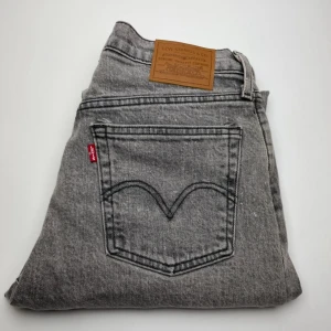 Grå Levi's 501 jeans  - Snygga grå Levi's 501 jeans med klassisk femficksdesign och ikonisk röd Levi's-tag på bakfickan. Jeansen har rak passform och är tillverkade i slitstarkt bomullsjeansmaterial. Perfekta för dig som gillar en tidlös och avslappnad look.