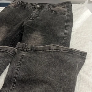 Mörkgråa bootcut jeans med tvättad look - Säljer ett par mörkgråa bootcut jeans med cool tvättad finish och klassisk femficksdesign. Jeansen är flared och normal passform, perfekta till sneakers eller boots. Materialet är slitstarkt denim och de har knapp och dragkedja framtill.