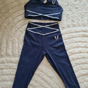 Set från firm abs nypris 1400 - Snygga mörkblå leggings från Firm Abs med hög midja och vita detaljer i form av korsande linjer framtill. Materialet är stretchigt och passar perfekt för träning. Tight passform som framhäver benen och sitter skönt under hela passet.  Storlek small och lite små I storleken. Inget att anmärka på. Nypris 1400 kr så kommer inte acceptera några bud, priset är redan toppen. 