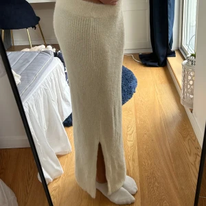 Vit stickad långkjol från Vero Moda - Megaaamysig vit/beige stickad långkjol från Vero Moda. Kjolen har en rak passform, ribbad struktur och en snygg slits. Funkar både att klä upp och ner! Är i storlek M men passar mig som är xs/s.