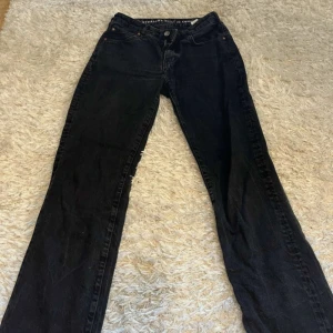 Svarta jeansbyxor - Snygga svarta jeansbyxor med låg midja och straight passform. De har klassiska femficksdetaljer och en dragkedja med knapp framtill.