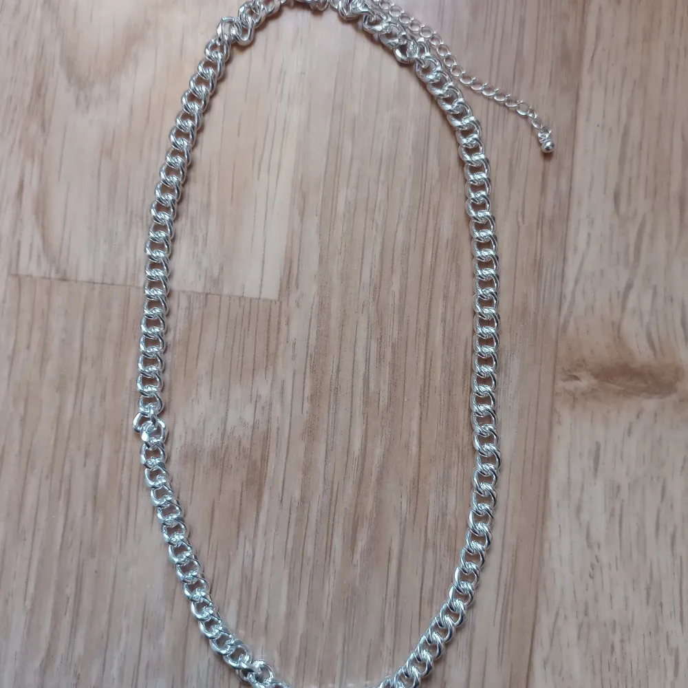 Snyggt silverfärgat halsband med kedjedesign. Perfekt för att ge en stilren touch till din outfit. Justerbar längd för bästa passform.. Asusteet.