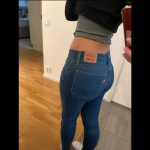 Levis 710 Super Skinny Jeans - Snygga Levis 710 Super Skinny jeans i en klassisk blå färg. De har en tight passform och är lågmidjade, vilket ger en modern och stilren look. Perfekta för att matcha med olika toppar och skor.