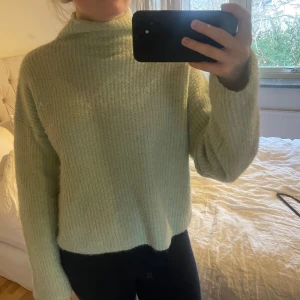 Ljusgrön/mint stickad tröja - Mysig ljusgrön/mint stickad tröja med hög krage och långa ärmar. Perfekt för kyliga dagar och ger en avslappnad look. Tröjan har en ribbad struktur som ger extra stil och komfort. Från Gina tricot storlek xs.