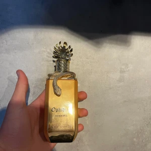 Guldparfym Ophidian från Paris Corner - Lyxig parfymflaska i guld med en unik design. Flaskan har en dekorativ orm runt halsen och ett detaljerat lock. Märkt med 'Ophidian' och 'mango bliss'. Perfekt för den som vill ha något utöver det vanliga. INSPIRERAD av GOD OF FIRE, skulle gissa på att det är UNGEFÄR 97ml kvar
