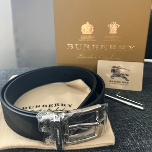 Burberry Bälte - Svart/grå bälte från Burberry. Helt nytt. Kommer med allt på bilden inklusive hålslagare.