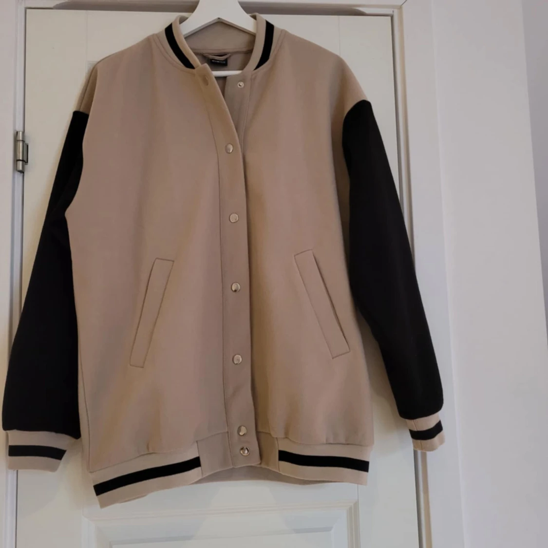 Beige och svart bomberjacka med text