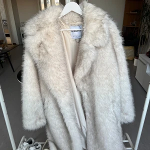 Vit pälsjacka från Bershka - Säljer en fluffig och stilren vit pälsjacka från Bershka. Jackan har en klassisk design med långa ärmar och en mjuk krage. Perfekt för att hålla sig varm och trendig under kyliga dagar. 