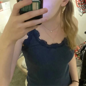 Blå ribbad linnetopp från Rosemunde - Säljer en snygg blå ribbad linnetopp från Rosemunde. Toppen har spetsdetaljer vid halsringningen och är tillverkad i en mjuk blandning av mullbärssilke och bomull. Perfekt för en stilren och bekväm look.