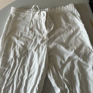 Vita linnebyxor med knytband - Snygga vita byxor med knytband i midjan och stora fickor framtill. Utsvängda/ baggy. Perfekta för sommaren!